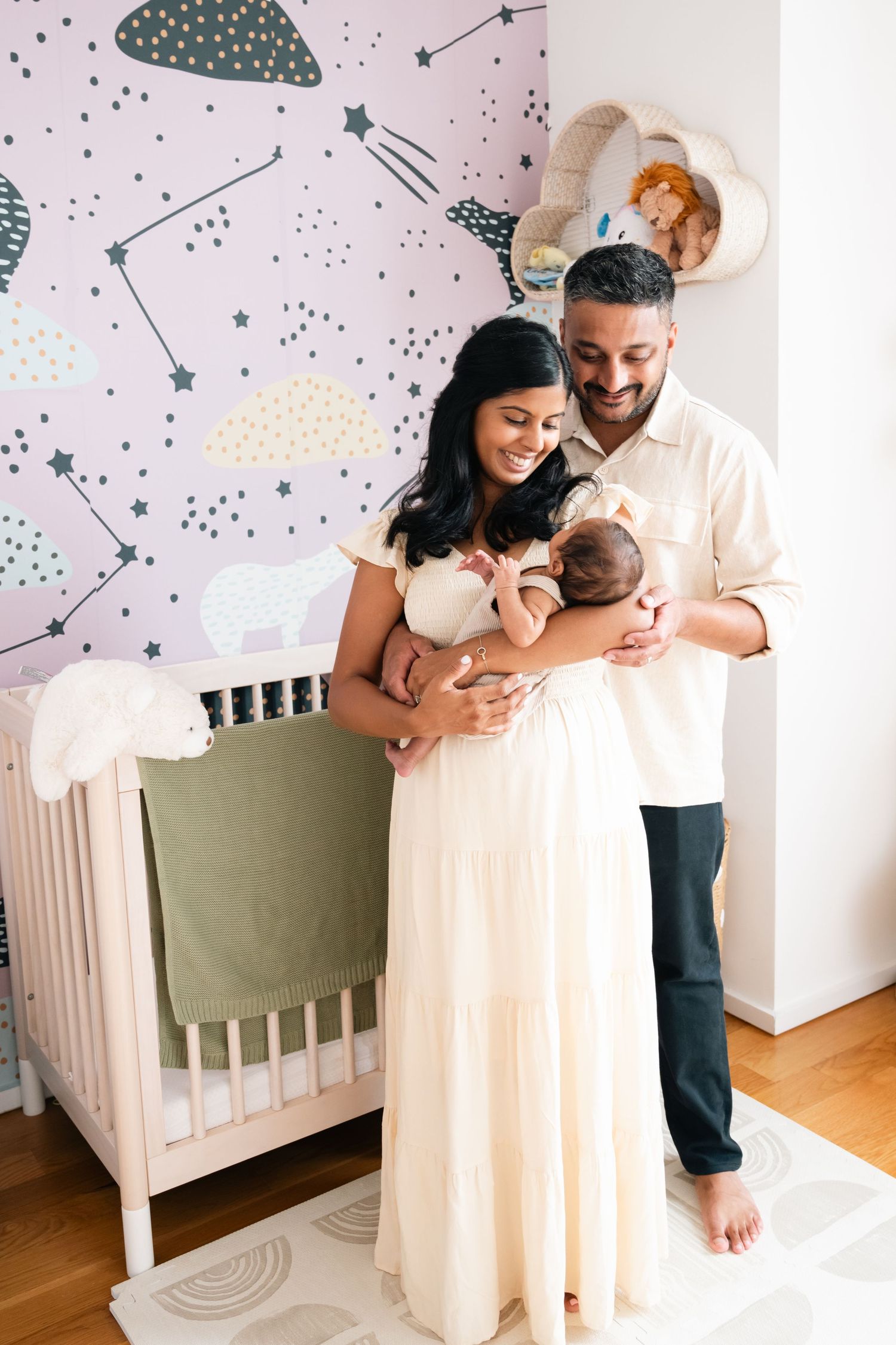 Nursery room with celestial wallpaper featuring stars and clouds in soft pastel colors.