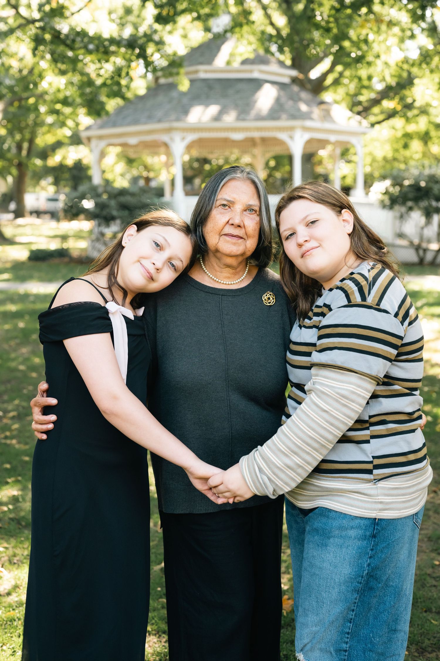 Three people embracing and sharing laughter together in a sunny garden setting.