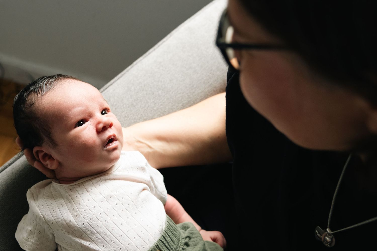 Dramatic lighting captures tender moment between caregiver and infant.
