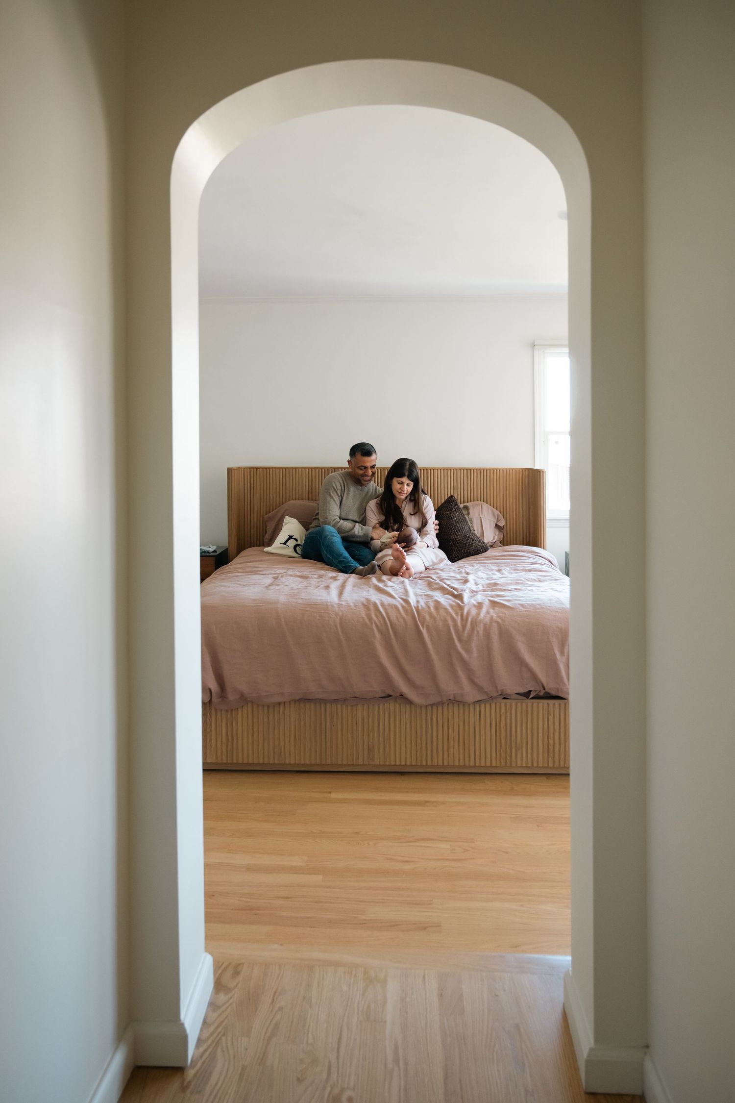 Minimalist white room with arched doorway and platform bed.