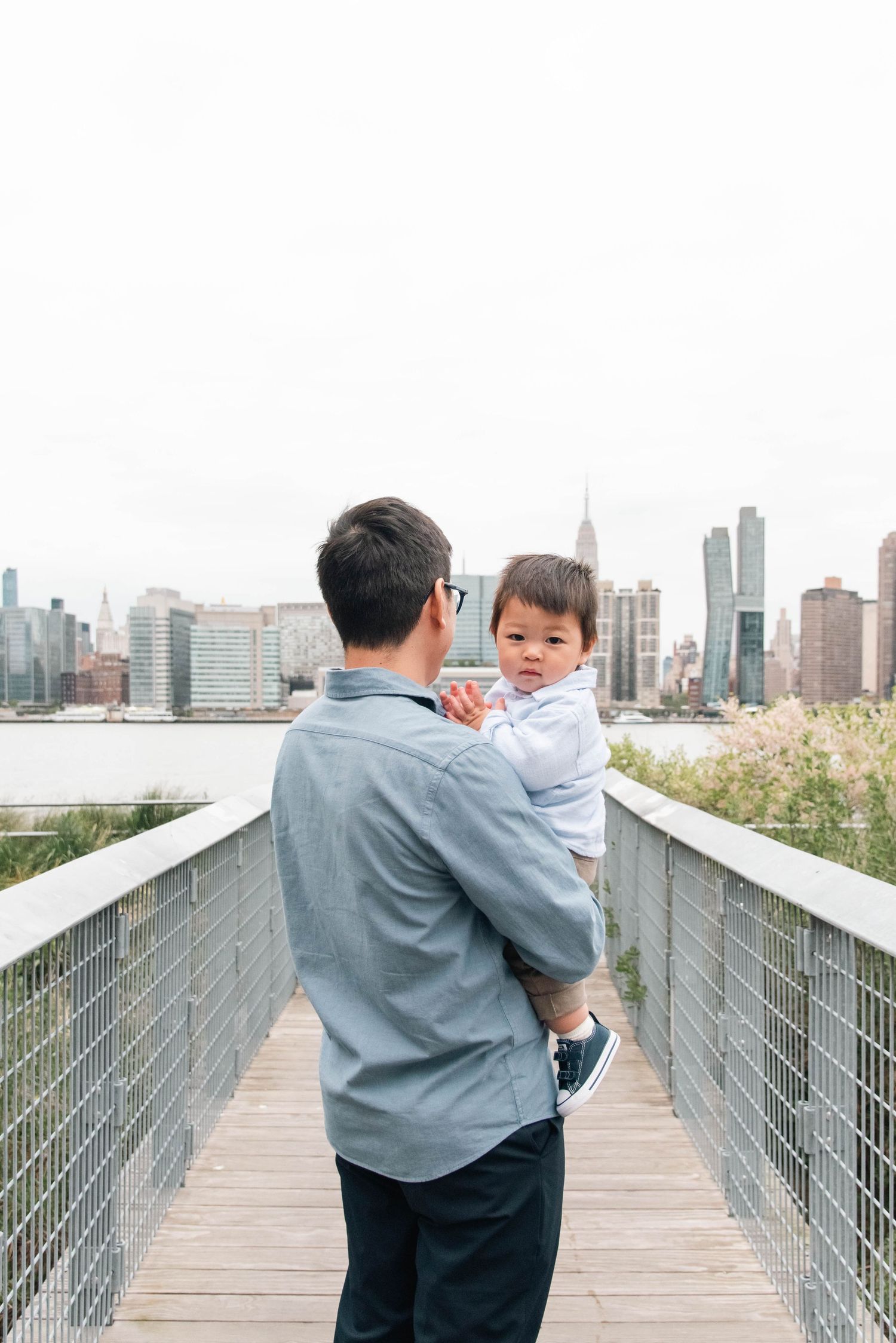 Parent and child looking at city skyline from elevated walkway.