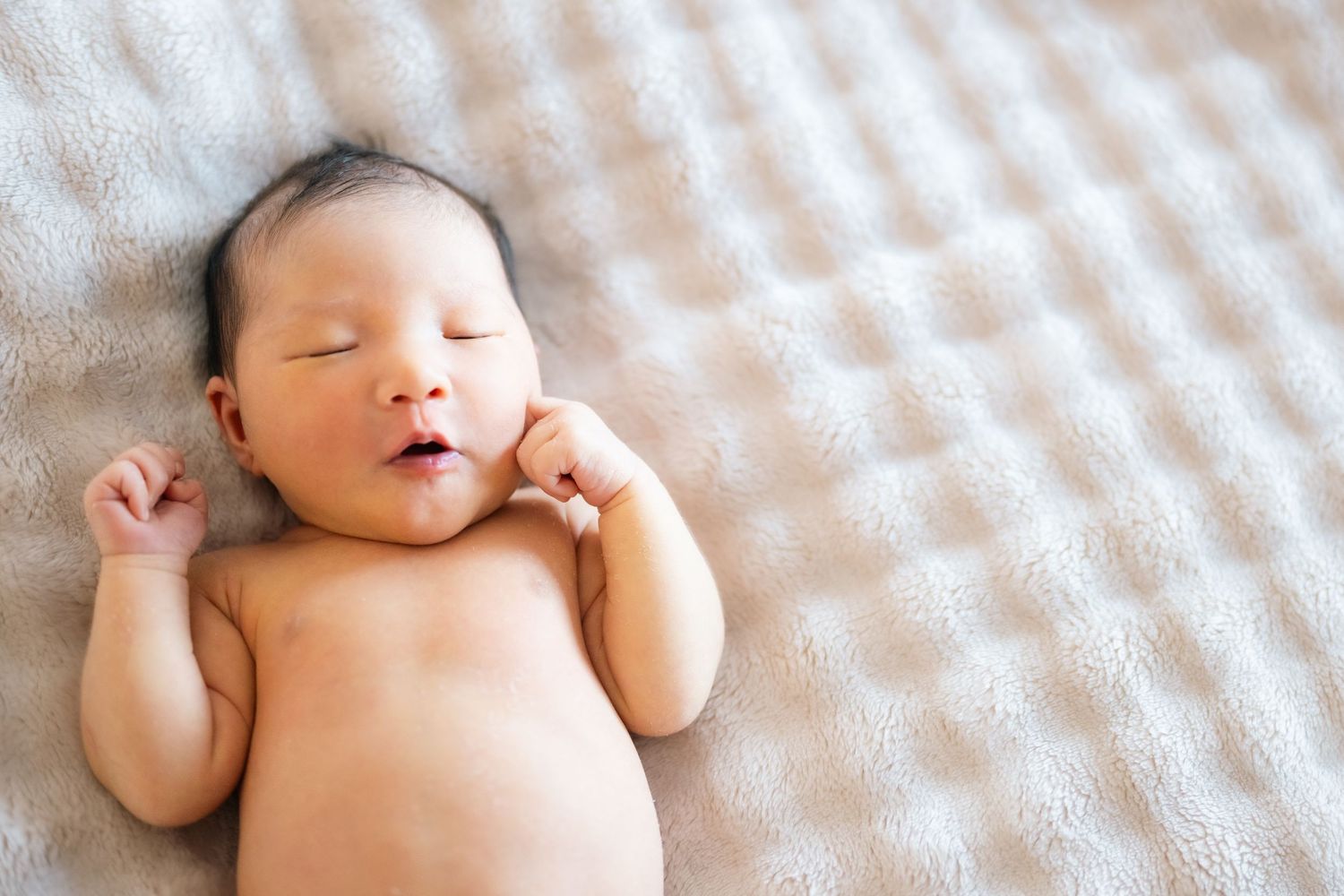 Newborn baby wrapped in white swaddle blanket sleeping peacefully.