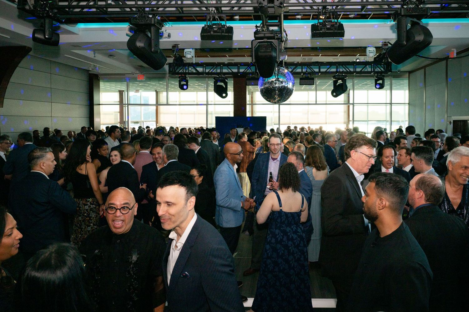 Large elegant gala event with formally dressed guests mingling in a spacious well-lit venue.