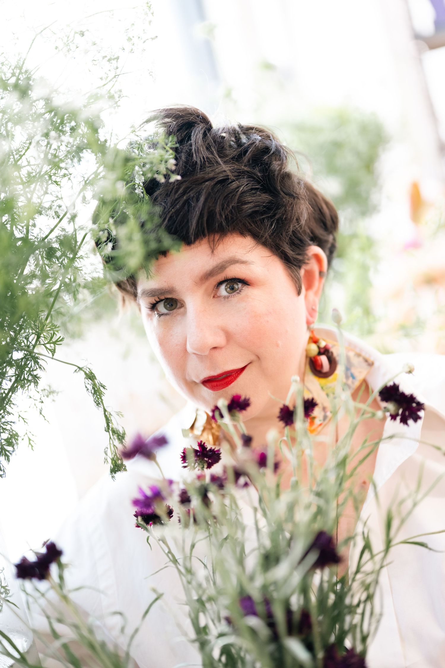 Artistic portrait with purple flowers and soft natural lighting creating a dreamy spring atmosphere.