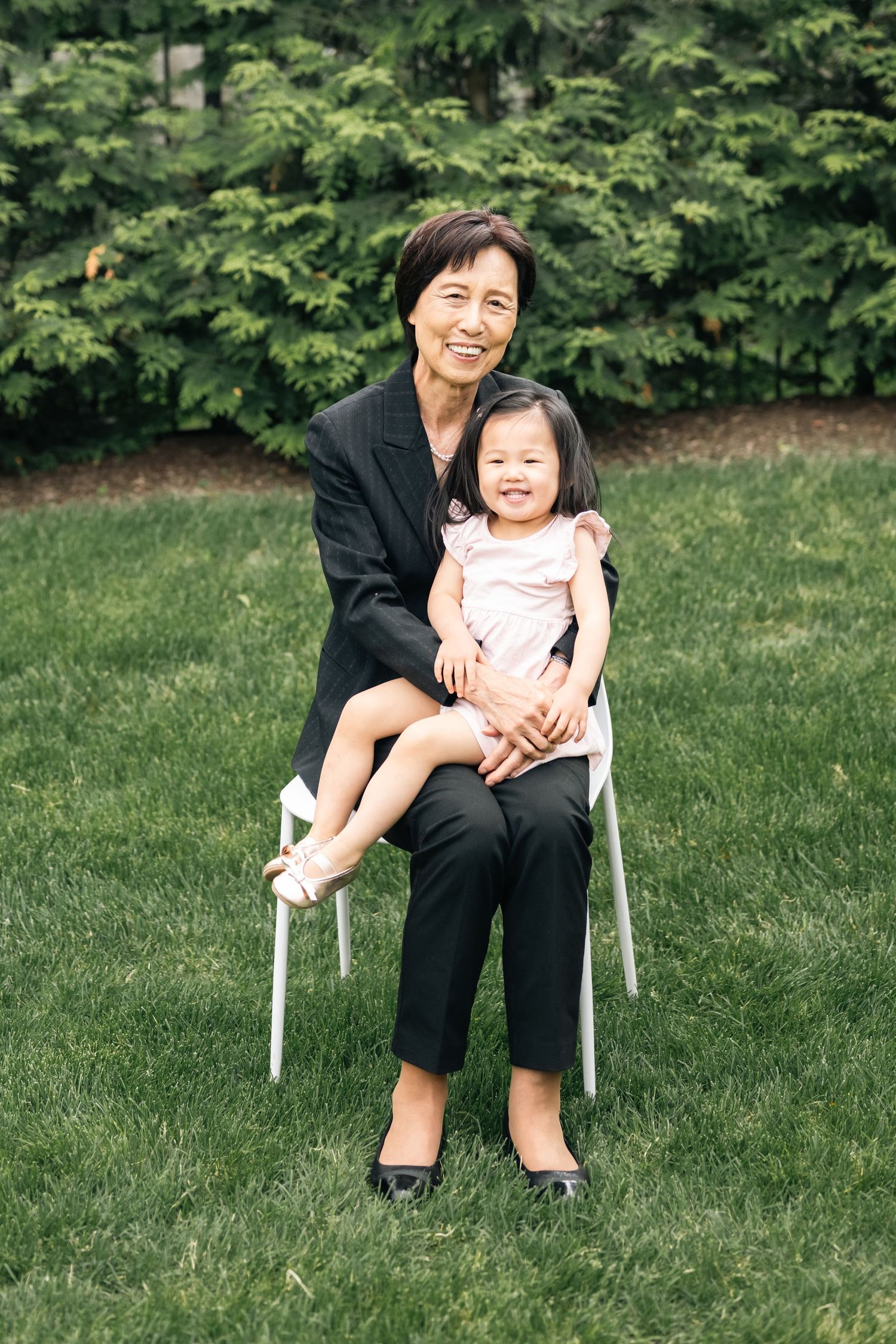 A heartwarming moment between family members sitting on a white chair in a garden setting.