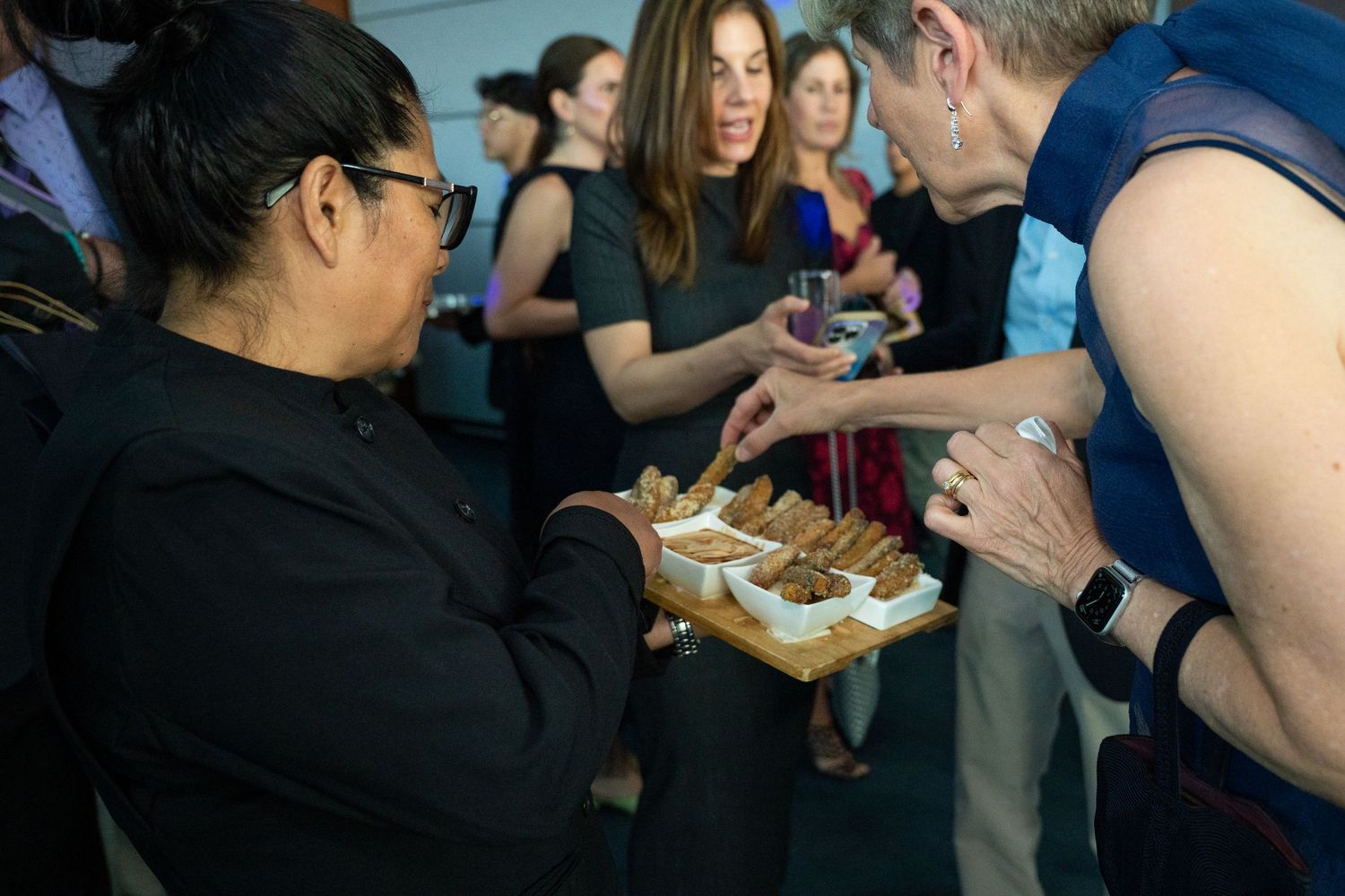 Server offers hors d'oeuvres on a tray to guests at an elegant cocktail reception event.