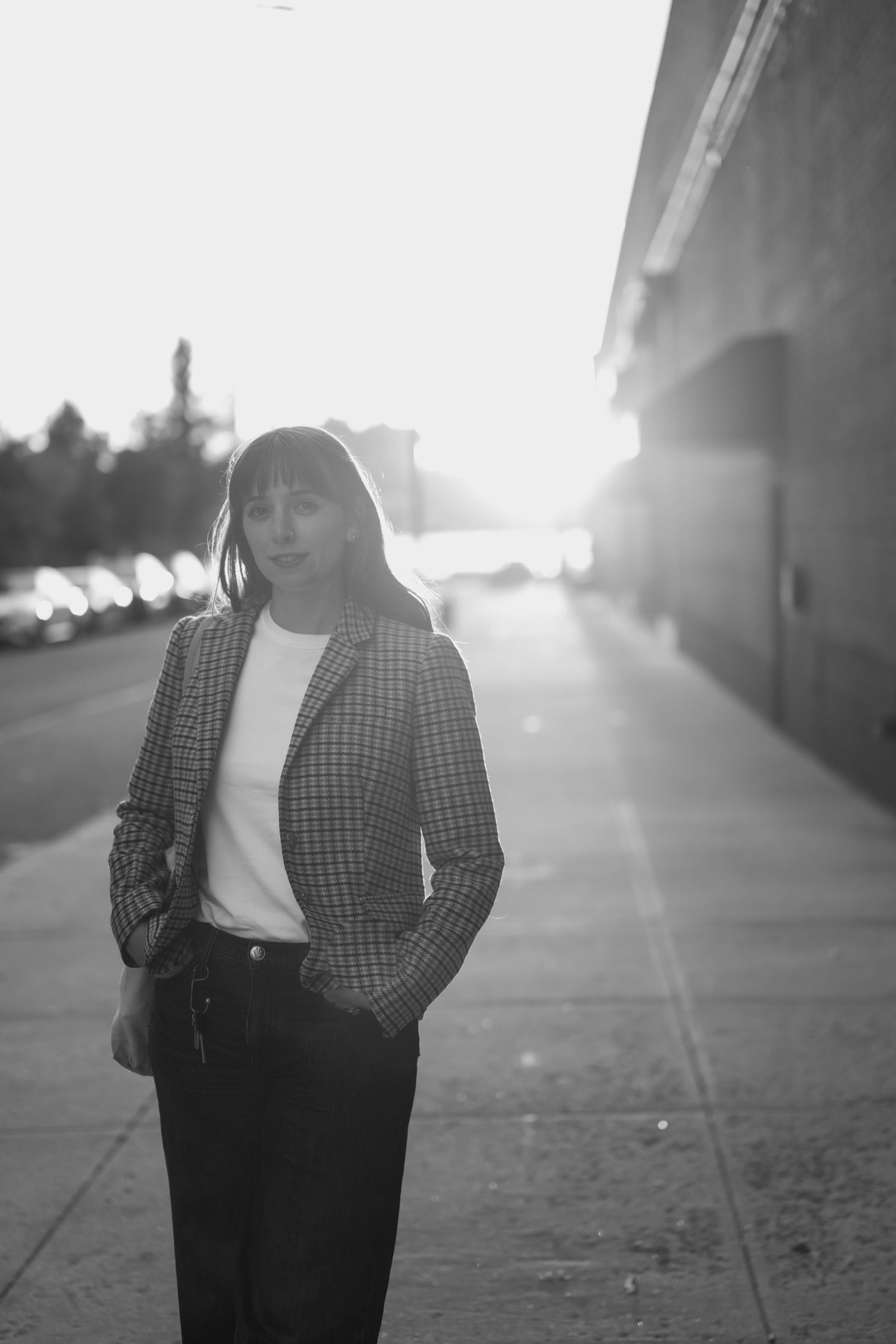 Black and white portrait series showing a person in a plaid jacket standing against a bright backlit urban setting.