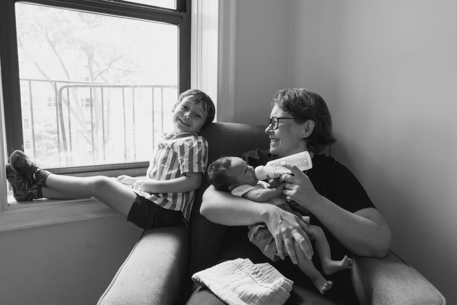 Two people lounging together by a window in a relaxed indoor setting.