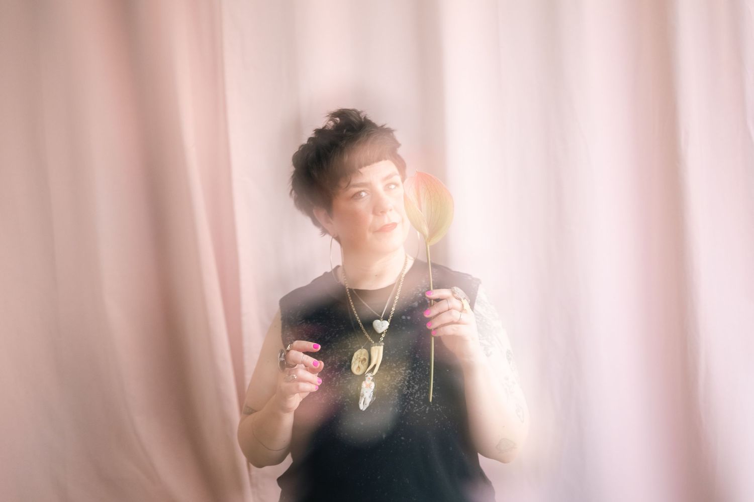 Dreamy portrait against pink backdrop with soft focus and light leaks.