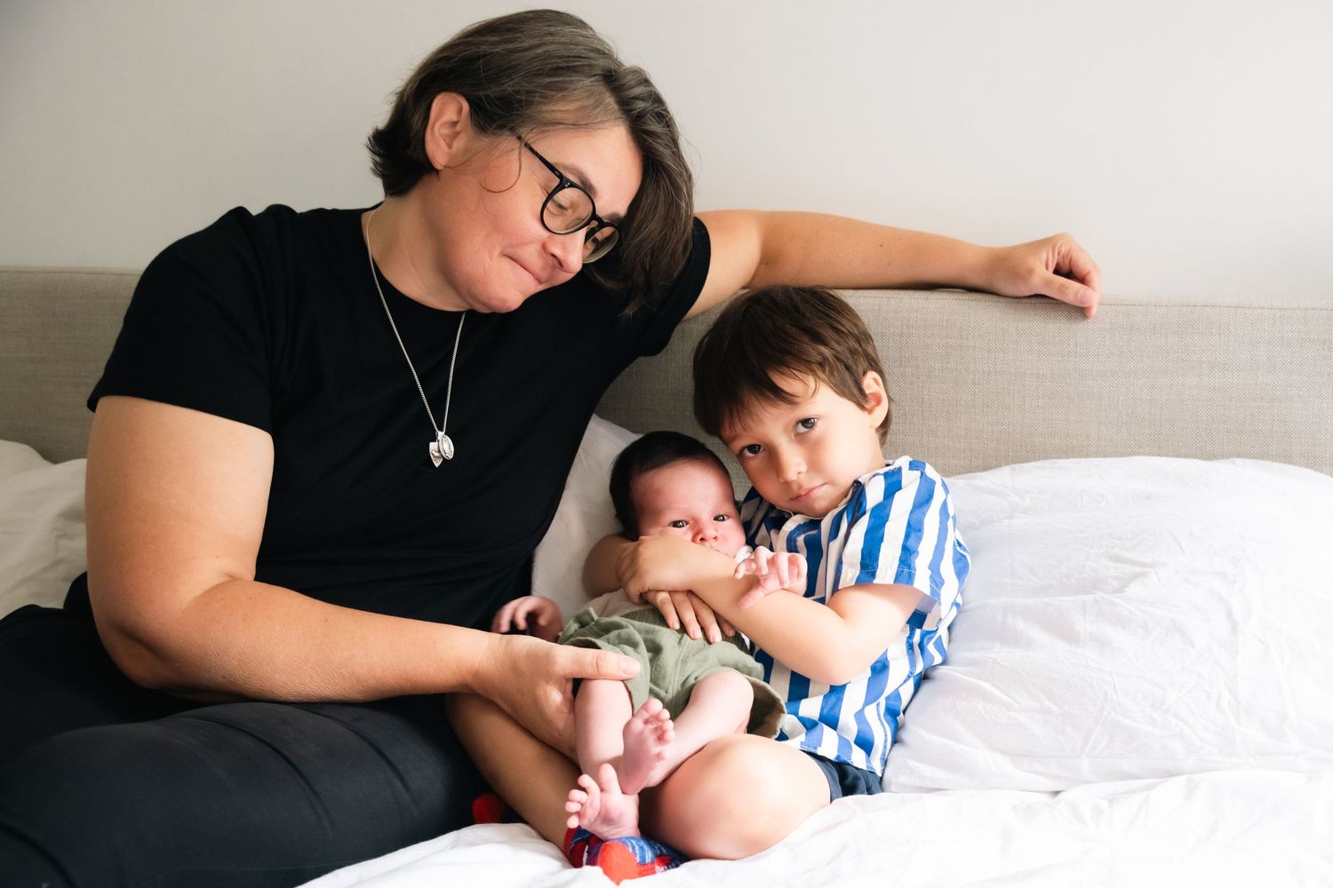 A tender family moment captured on white bedding showing gentle interaction and bonding.