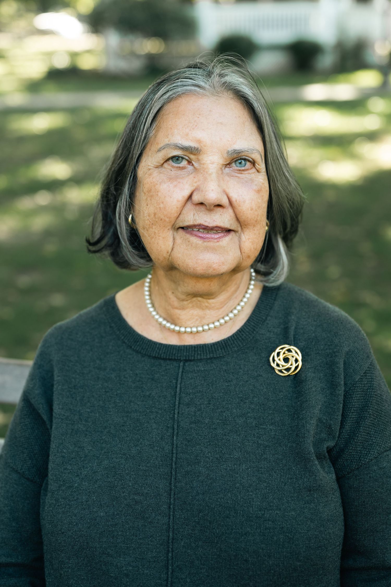 Portrait series showing a person wearing a black sweater and pearl necklace with a golden brooch.