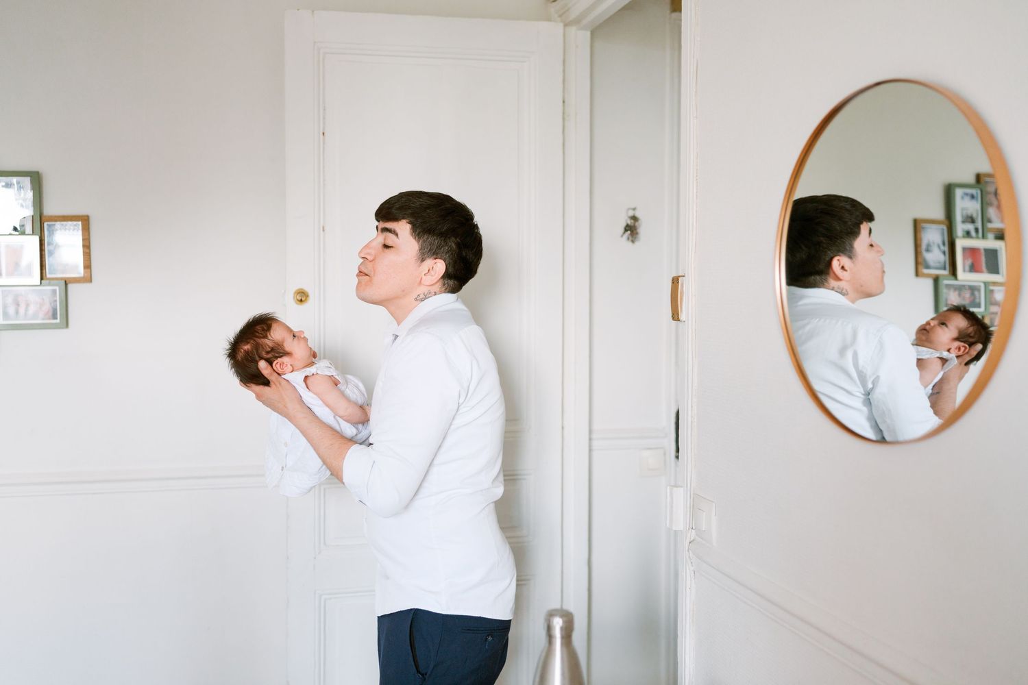 Jeune couple complice s’enlaçant dans une pièce lumineuse, avec leur reflet visible dans un miroir.