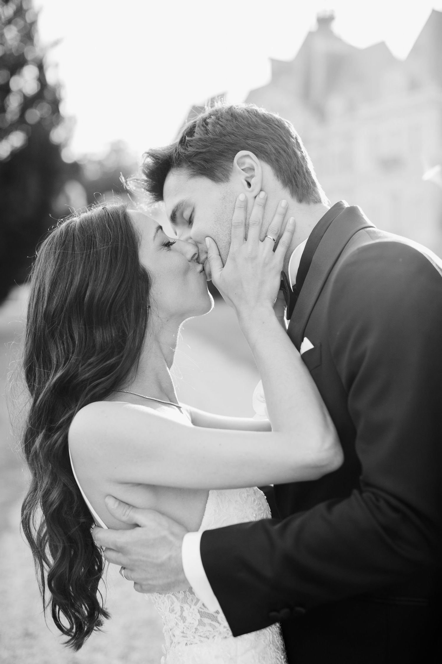 Black and white photo of a bride and groom sharing a romantic kiss on their wedding day.
