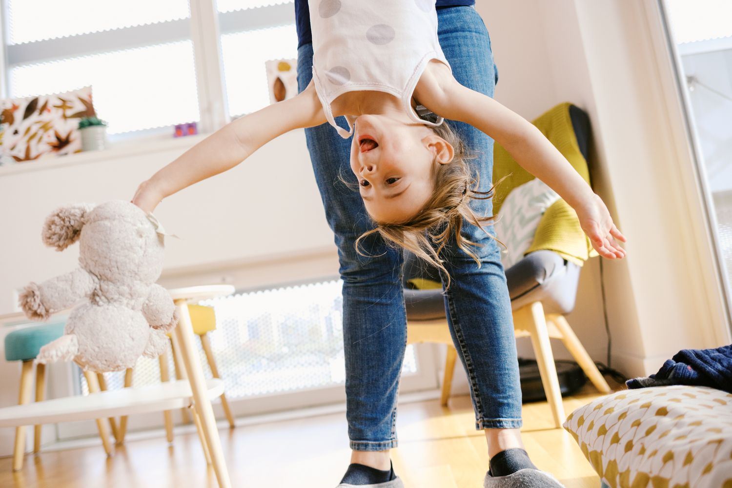 Parent and child playing together in a bright indoor room with toys and natural light.