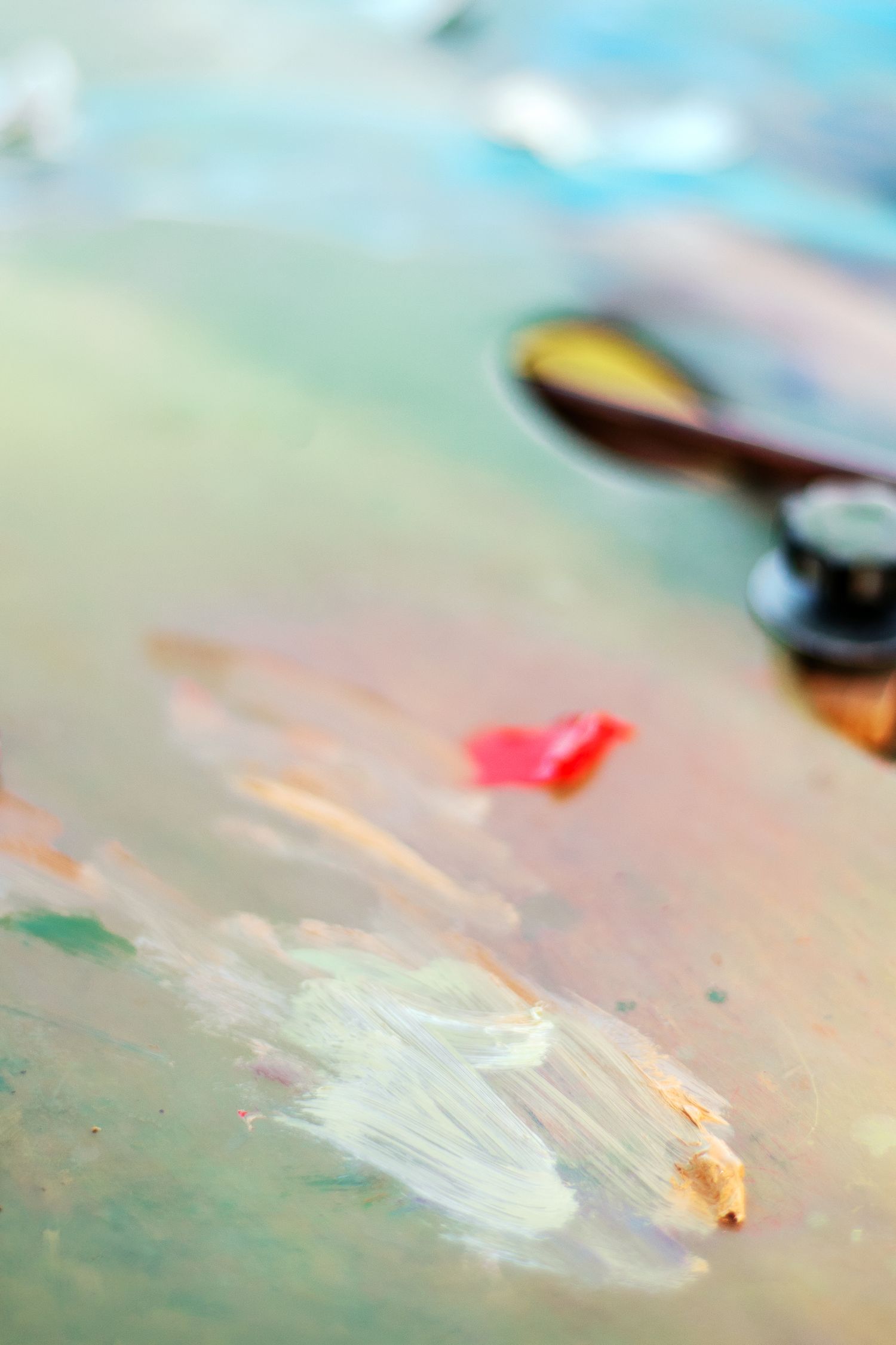 Close-up of a colorful artist palette with mixed oil paints, a palette knife, and vibrant paint strokes in soft focus.
