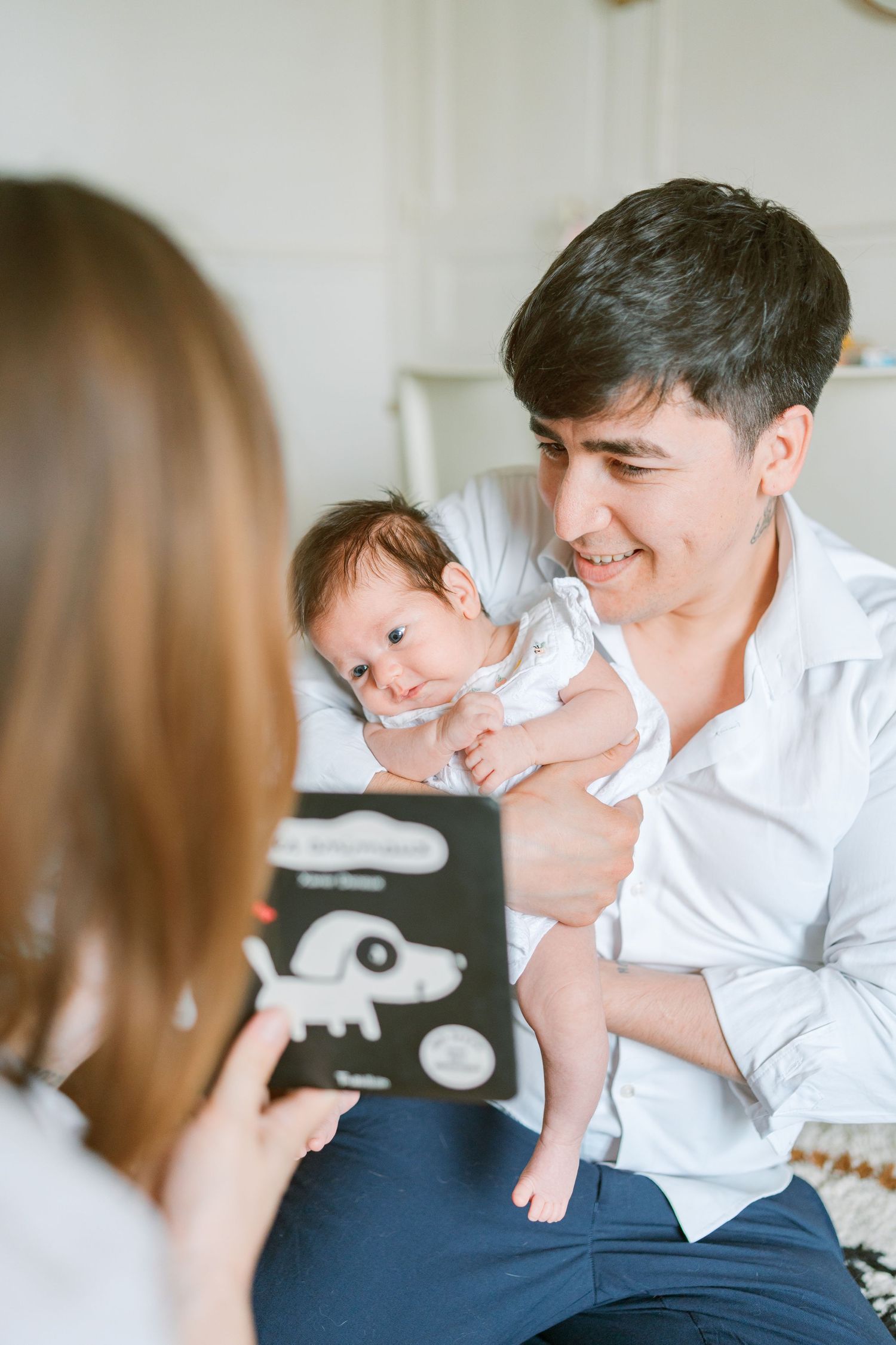 Une famille passe un moment de qualité à la maison avec leur nouveau-né tout en tenant un livre d'images.