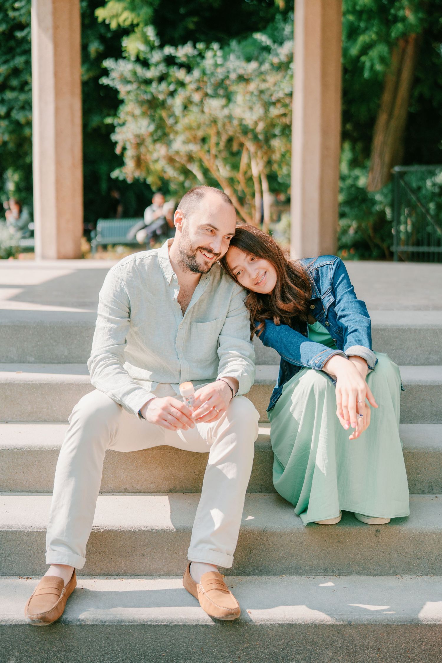 A couple sitting on outdoor steps together sharing a tender moment on a sunny day.