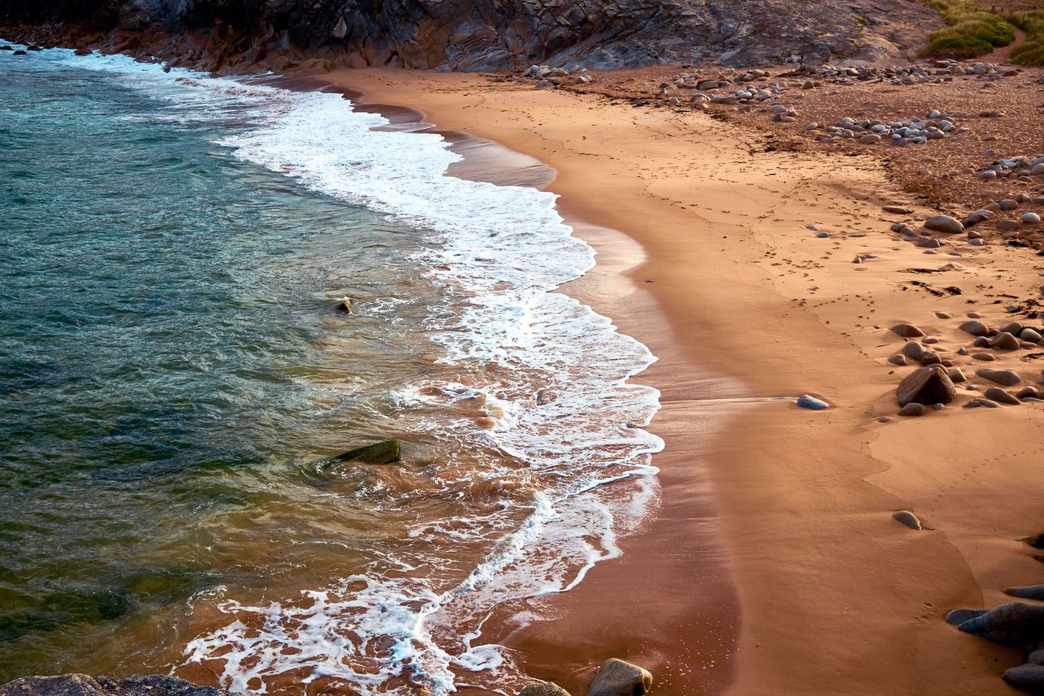 A scenic aerial series of beach shoreline with turquoise waters meeting sandy coastline and rocky outcrops.