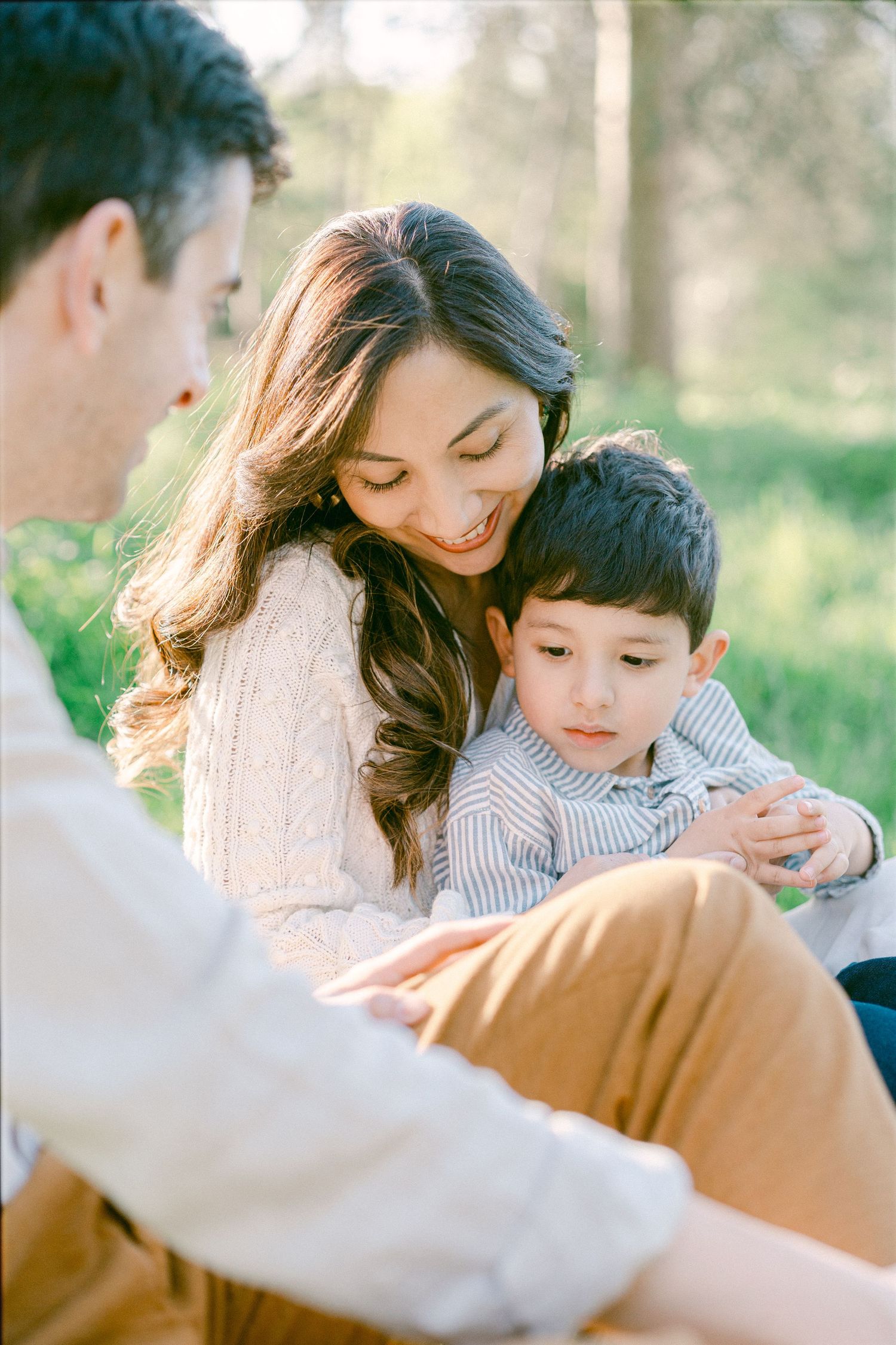 A family shares tender moments together in a sunny outdoor setting during a lifestyle photo session.