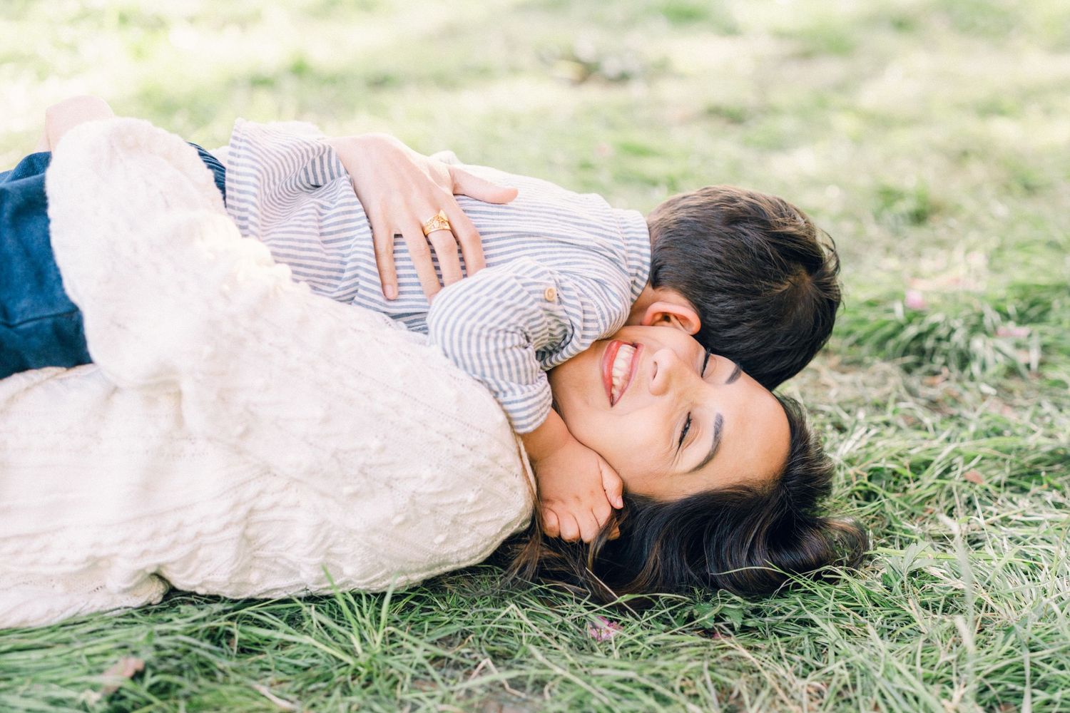 Parent et enfant allongés ensemble dans l’herbe, partageant un moment de tendresse.