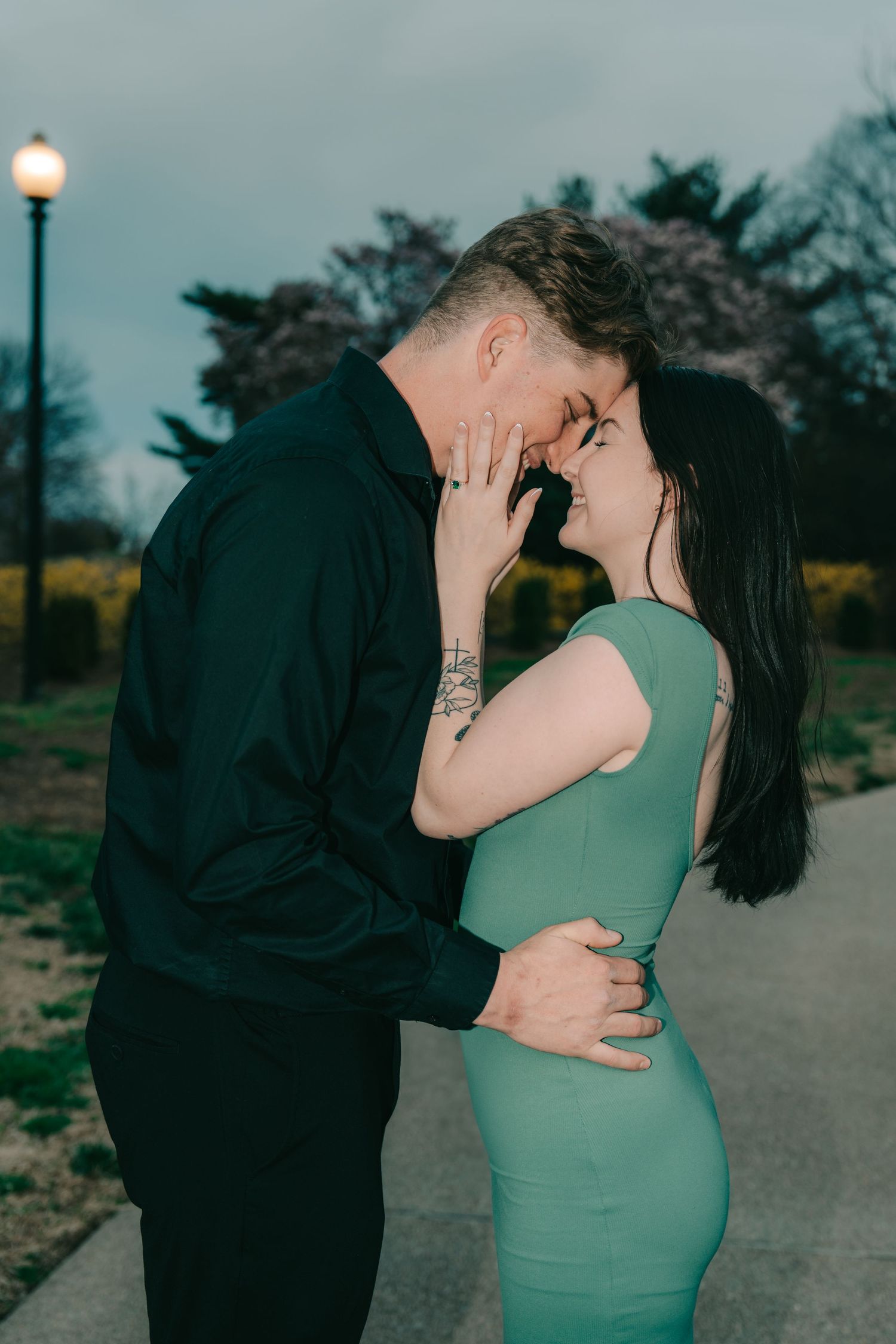 Romantic couple sharing an intimate moment at dusk, with a street lamp glowing in the background.
