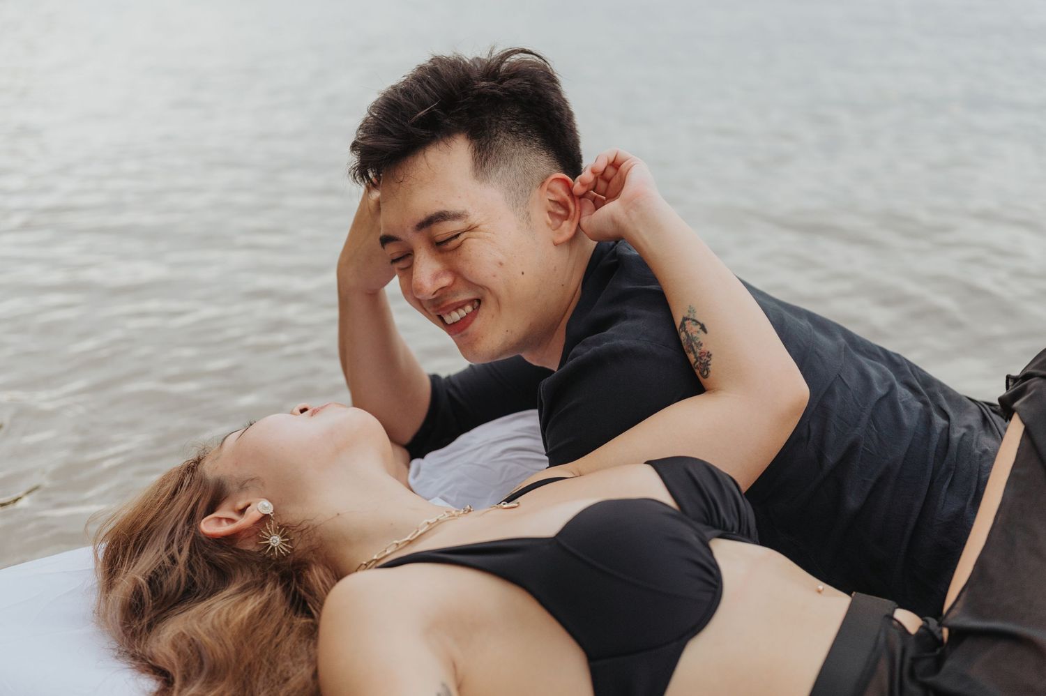 Couple dressed in black sharing intimate moments on floating mattress.
