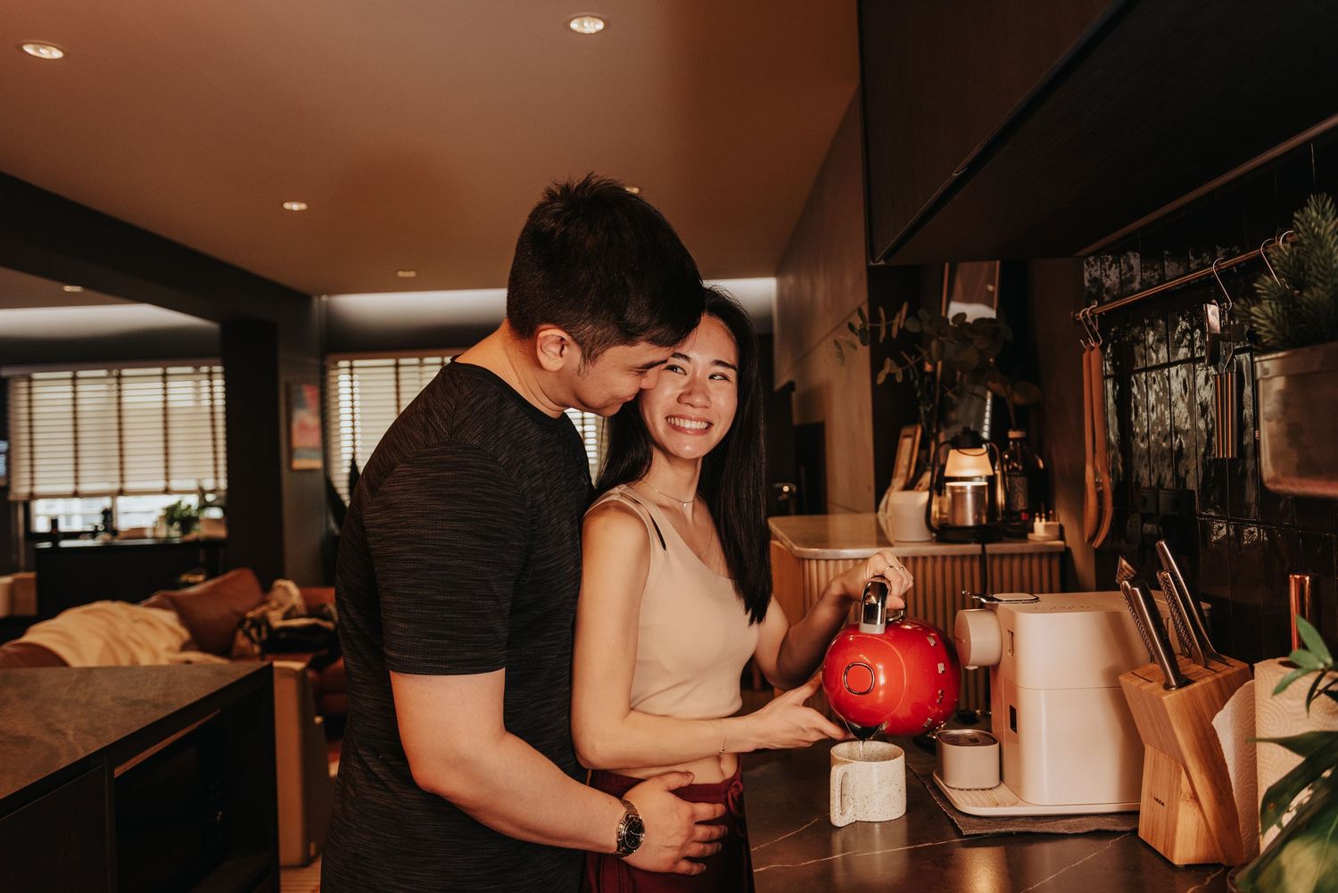 A sweet interaction between a couple in a modern kitchen with warm ambient lighting.