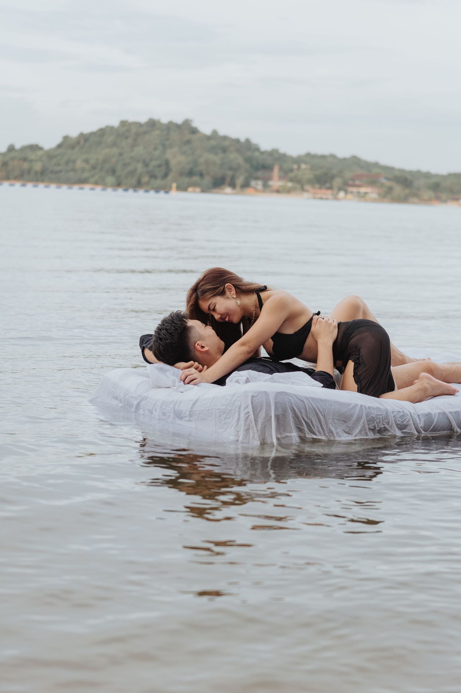 Romantic lake photoshoot with mattress floating on calm waters.