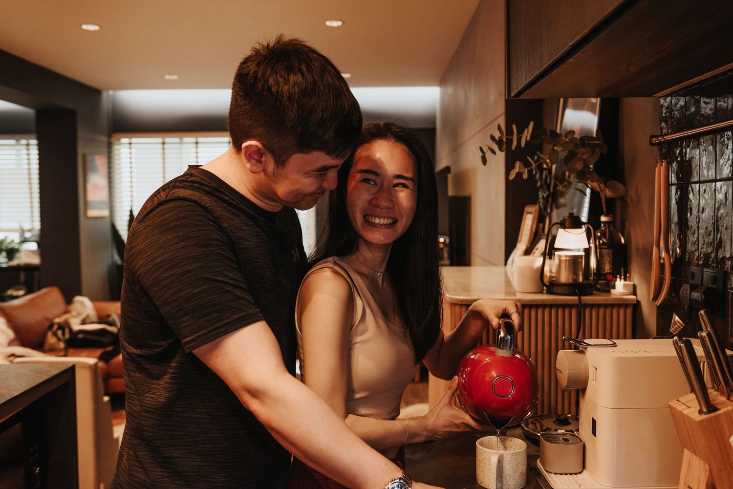 A joyful kitchen scene with warm lighting and a bright red appliance on the counter.