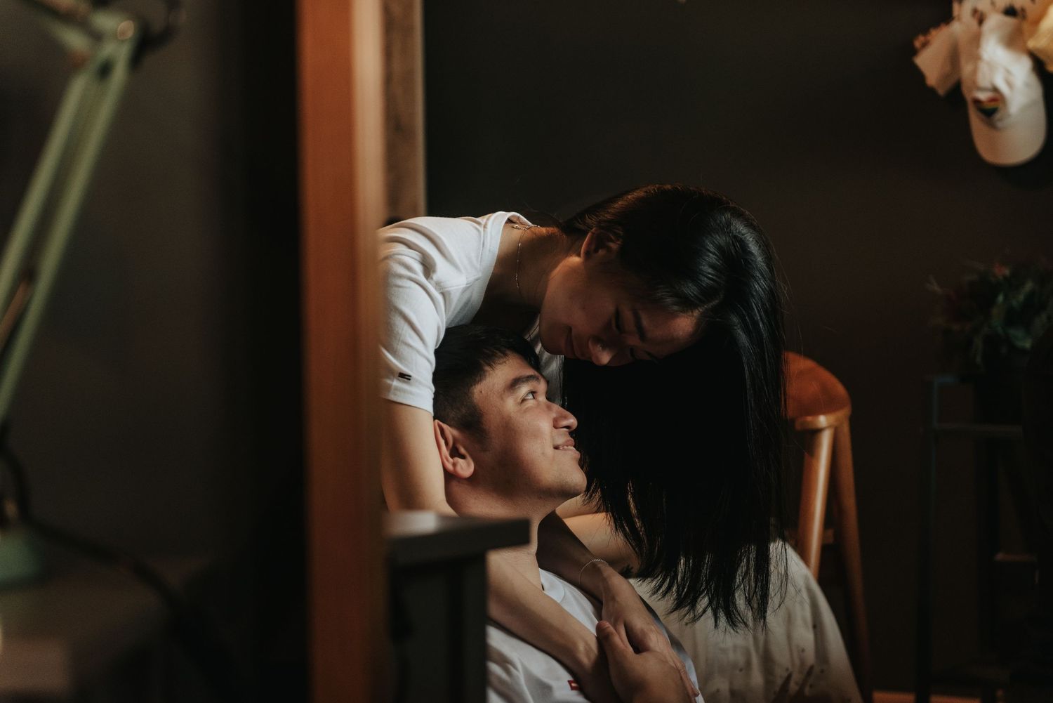Intimate lifestyle portrait of a couple sharing playful moments in a moody setting.