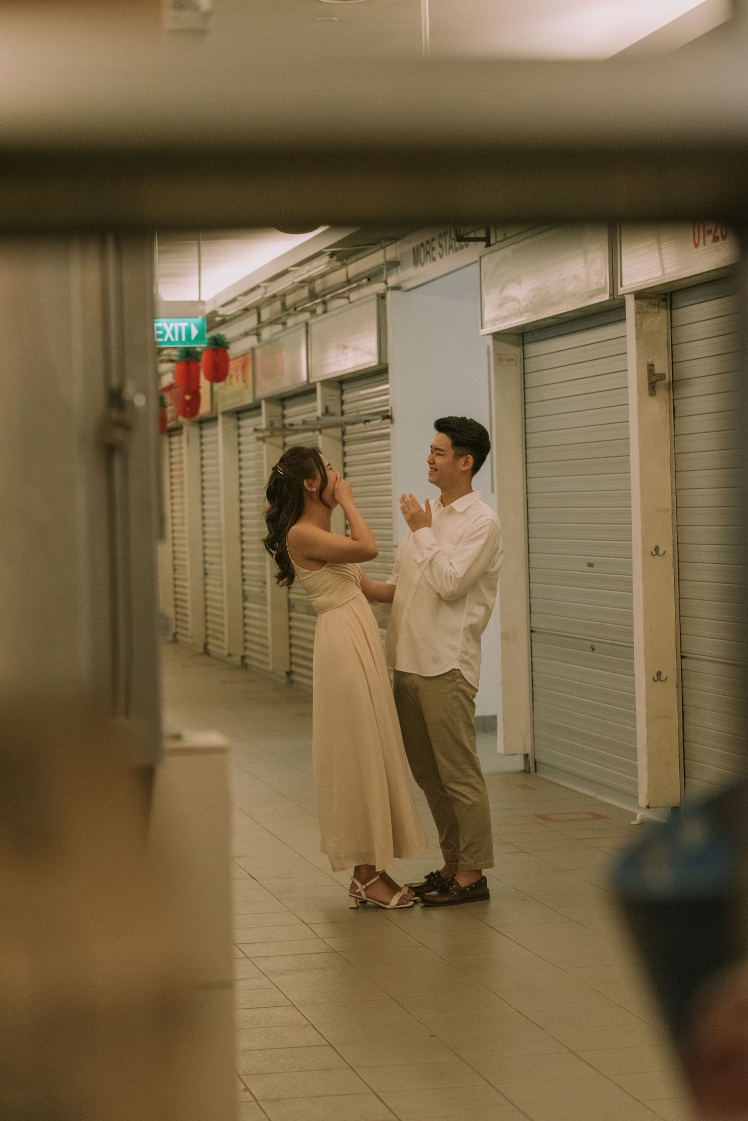 Couple sharing a tender moment in a mall corridor captured through an artistic frame.