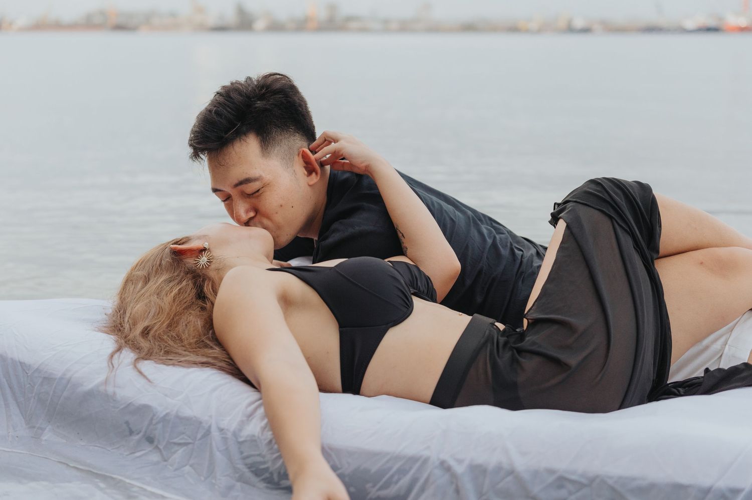 Playful couple sharing romantic moments while floating on mattress in lake.