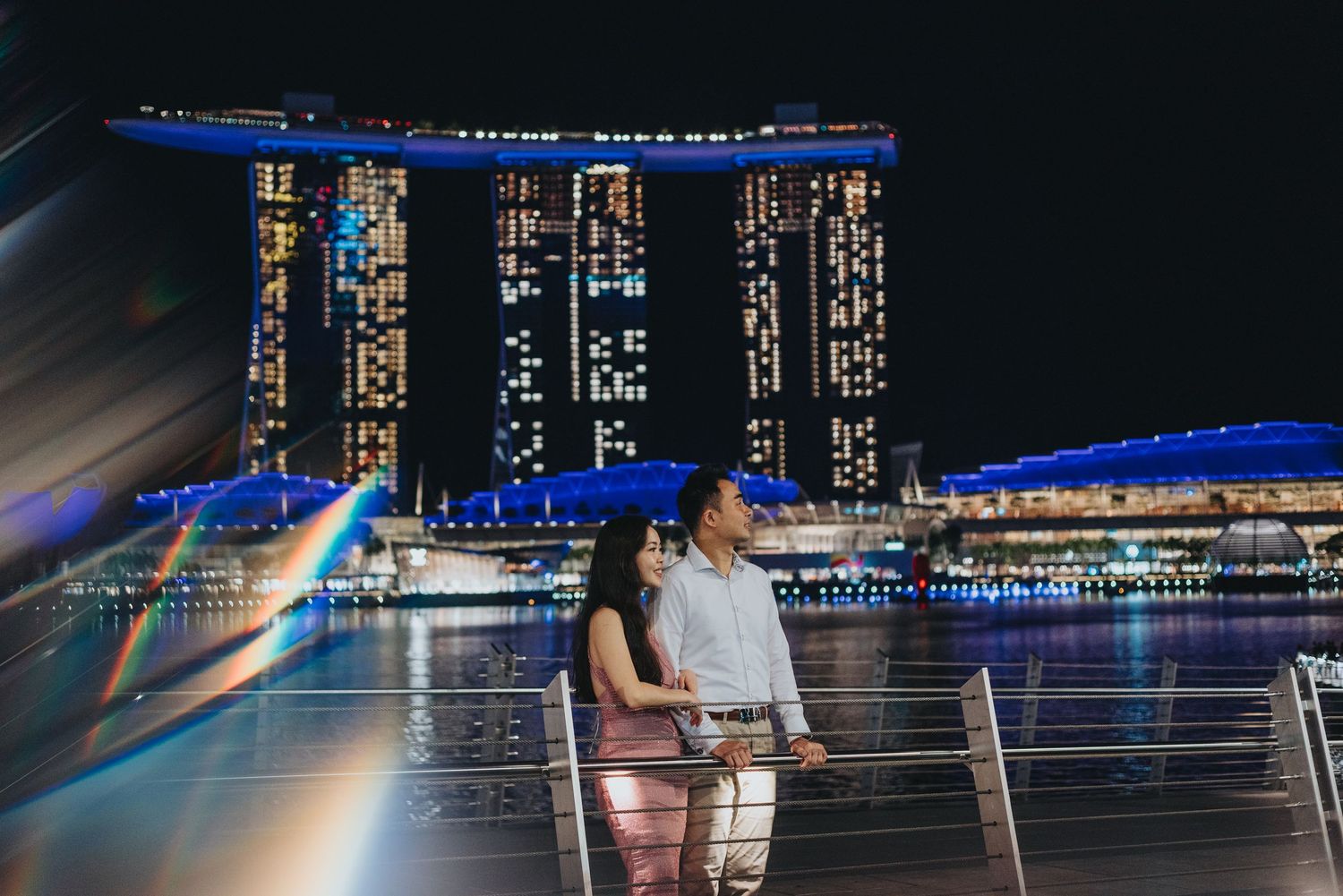 Romantic nighttime portrait with Singapore's Marina Bay Sands illuminated in the background.