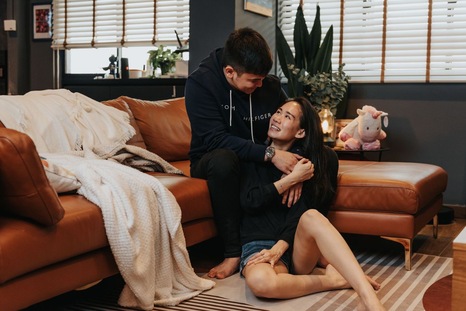 A tender moment shared between two people on a leather couch with throw blankets.