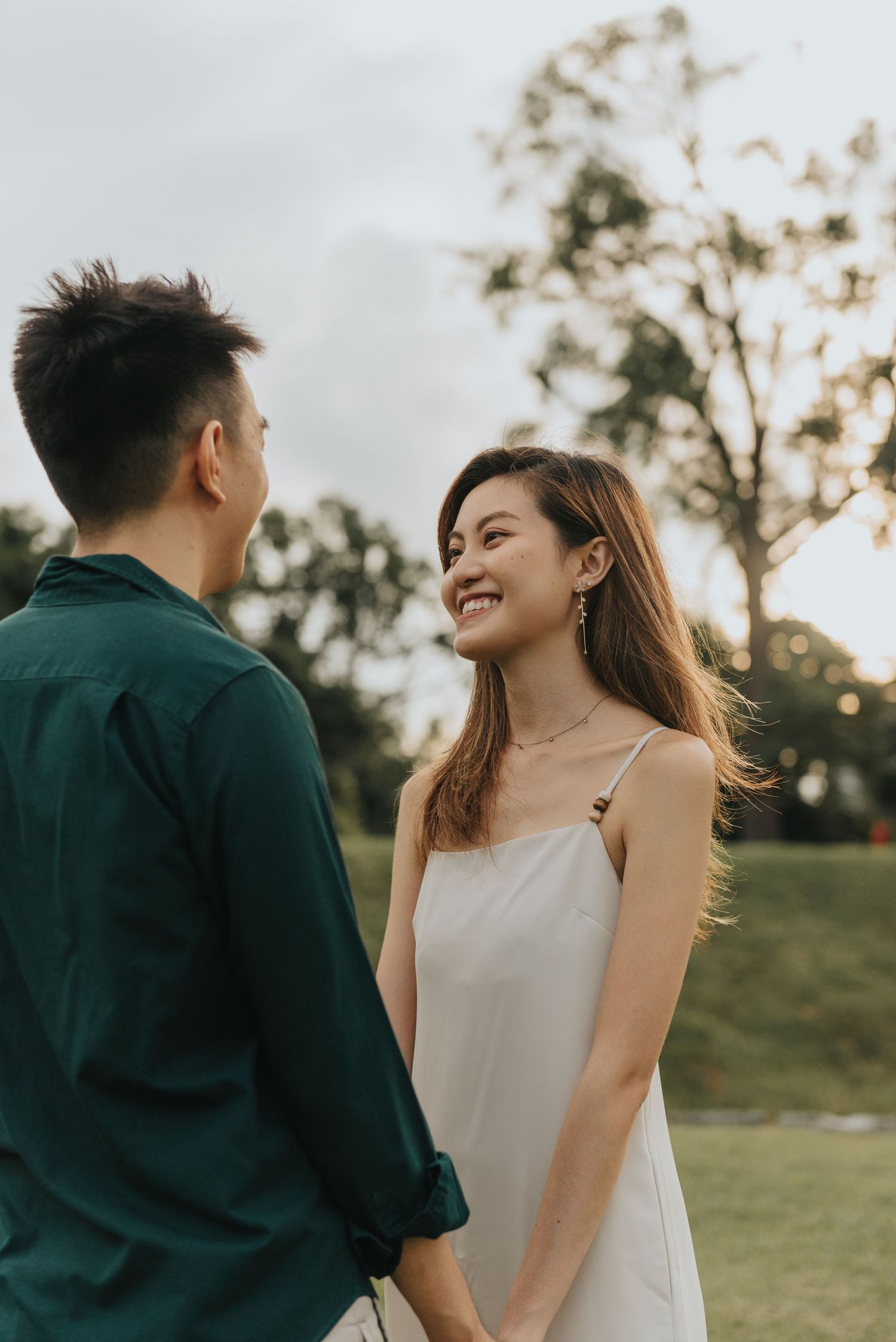 Couple in contrasting outfits sharing a joyful moment outdoors at sunset.
