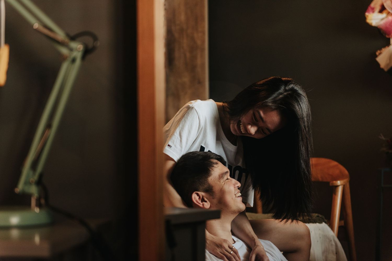 Romantic indoor photoshoot featuring a couple in white shirts against a dark background.