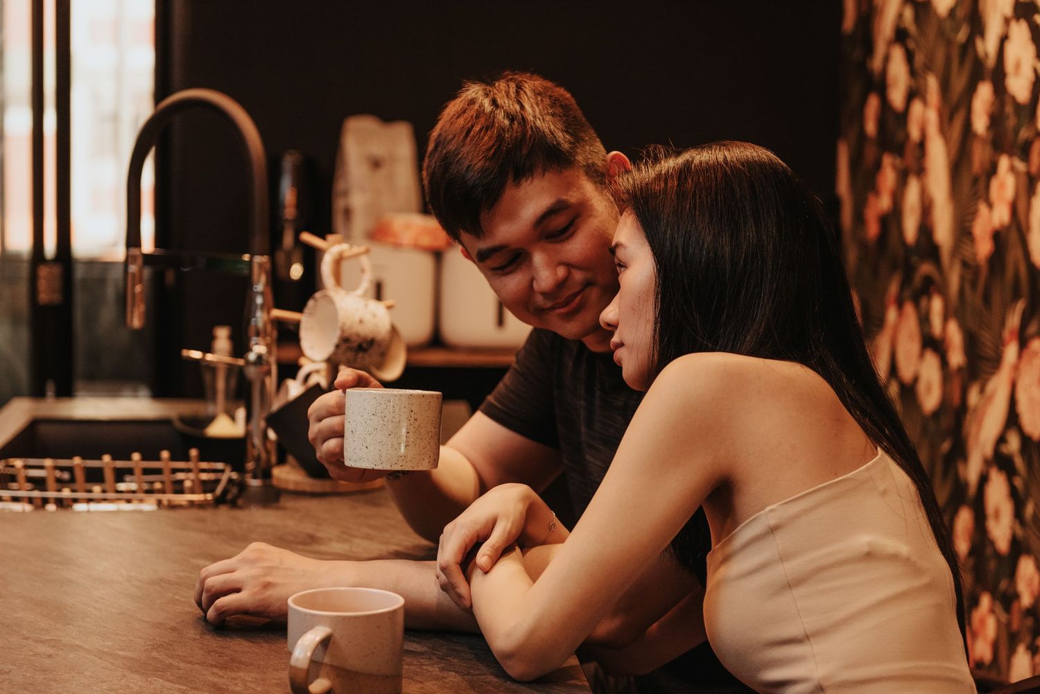 A romantic coffee date captured in warm tones as a couple shares intimate moments at a wooden table.