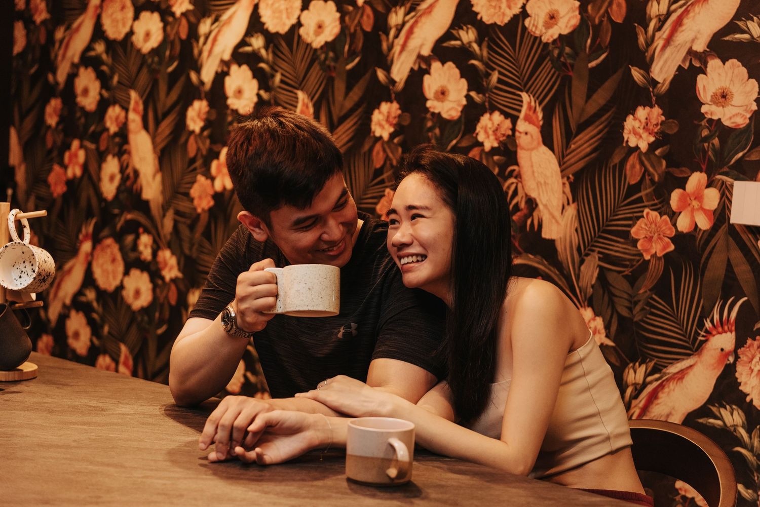 A cozy cafe scene with floral wallpaper background and warm lighting creating an intimate atmosphere.