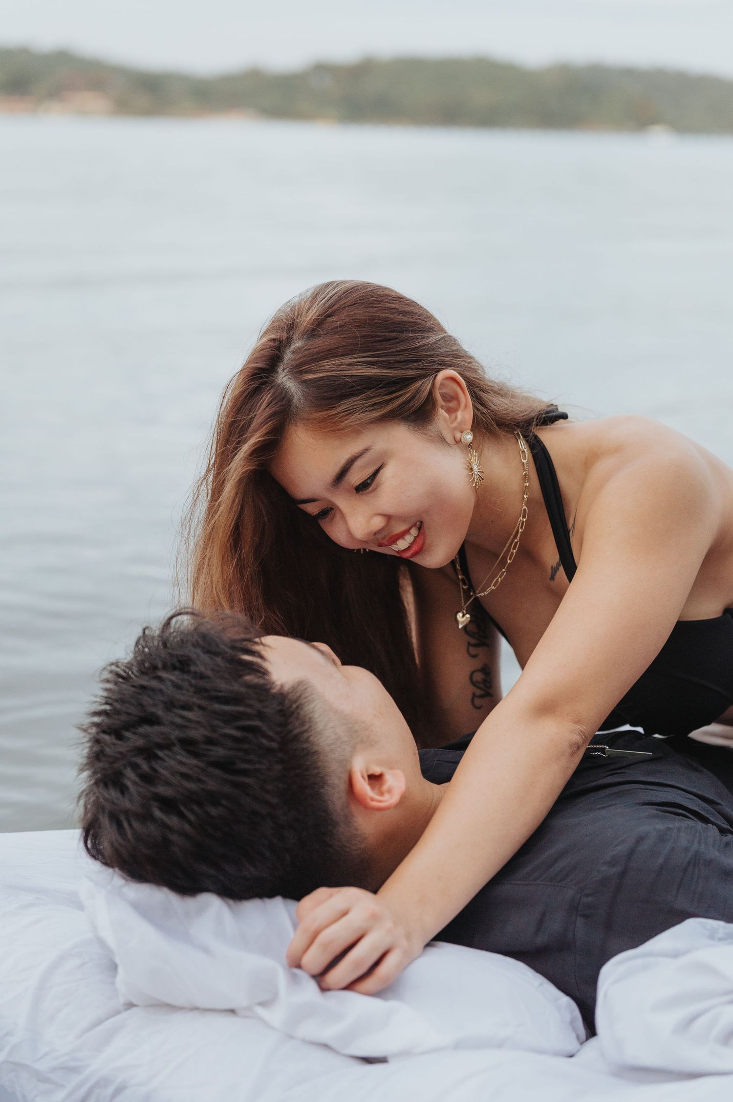 Couple embraces on white mattress floating in peaceful lake waters.