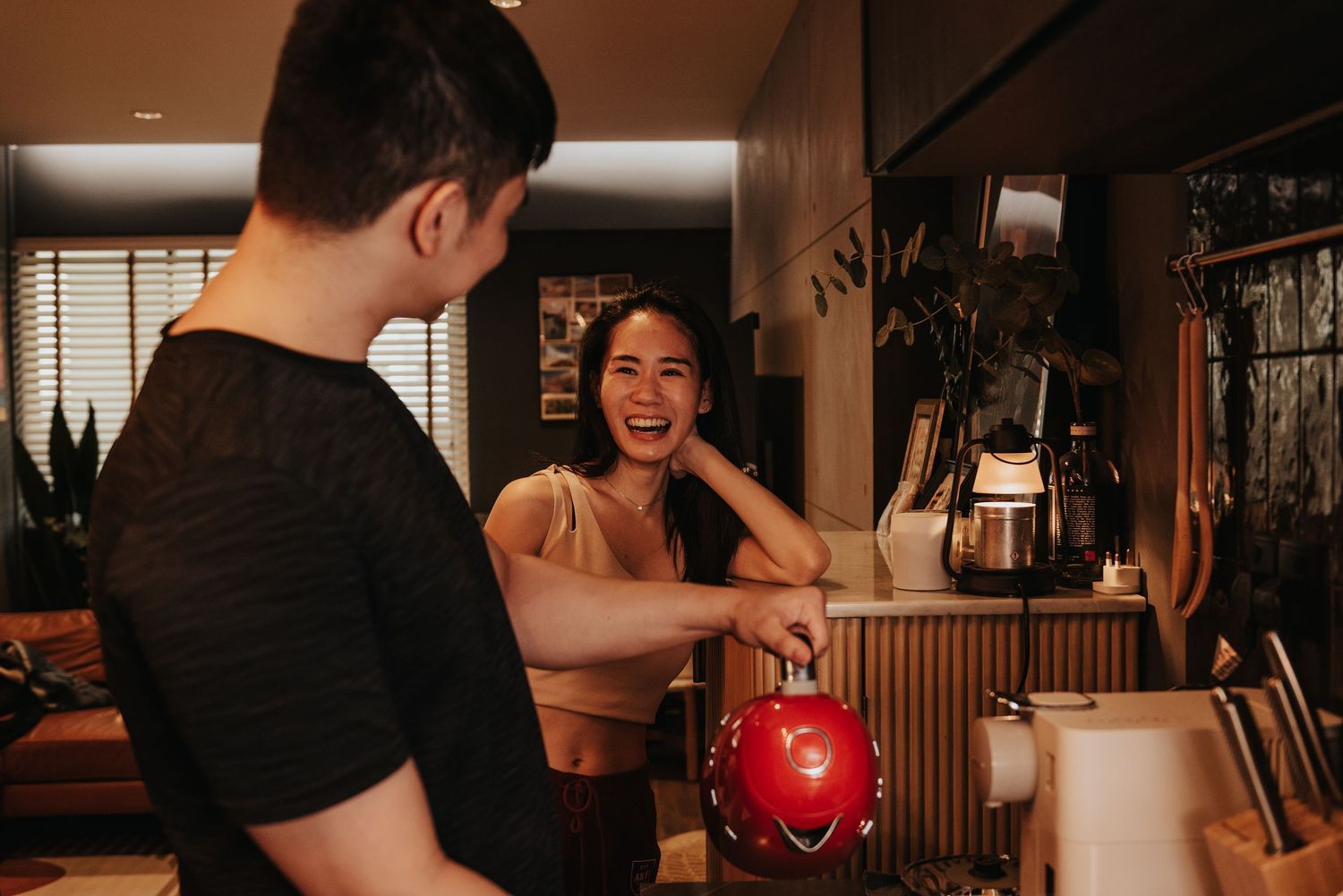 A candid moment of laughter in a modern kitchen with pendant lighting and minimalist decor.