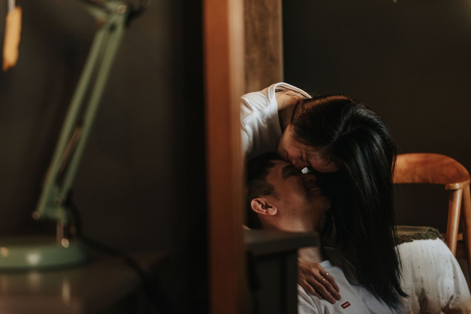 Romantic couple embracing in an intimate moment with soft lighting and minimal decor.
