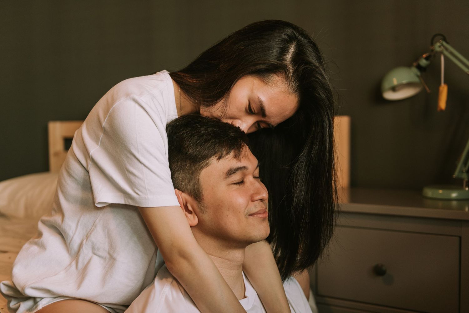Couple sharing an affectionate embrace in a dimly lit room with vintage decor.