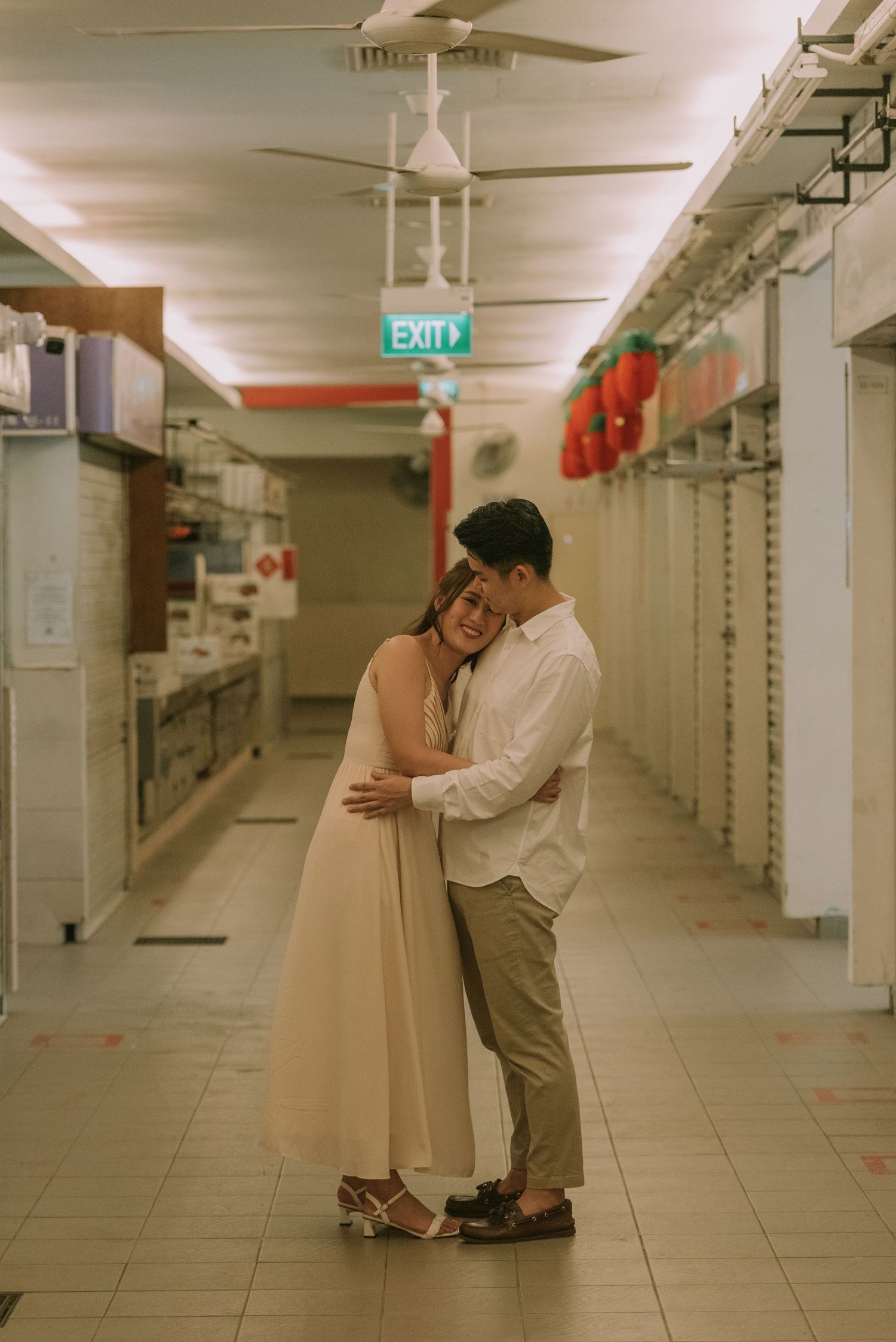 Intimate embrace between couple in formal attire standing in an industrial hallway.