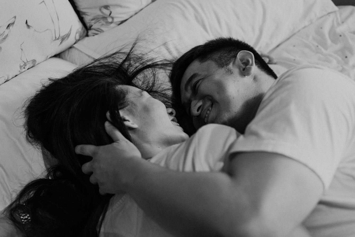 Intimate black and white portrait of couple in bed.