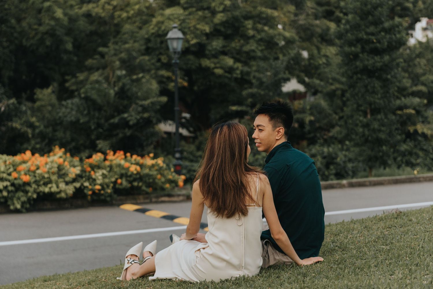 Couple spending time together on grassy lawn near colonial-style building.