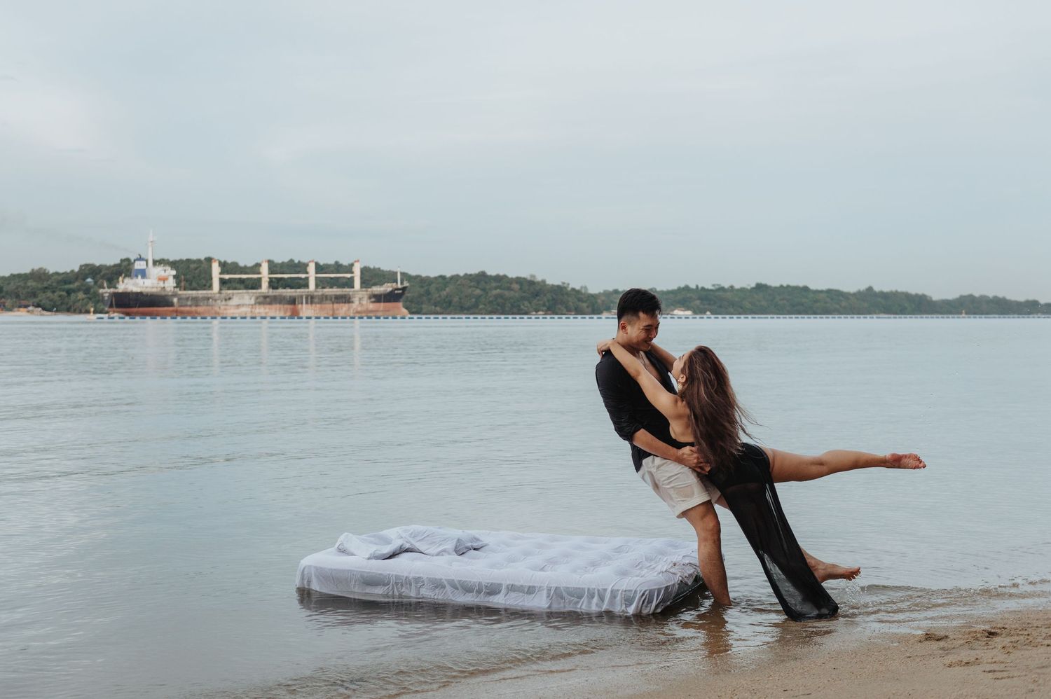 Intimate beach photography session featuring couple on white bedding.