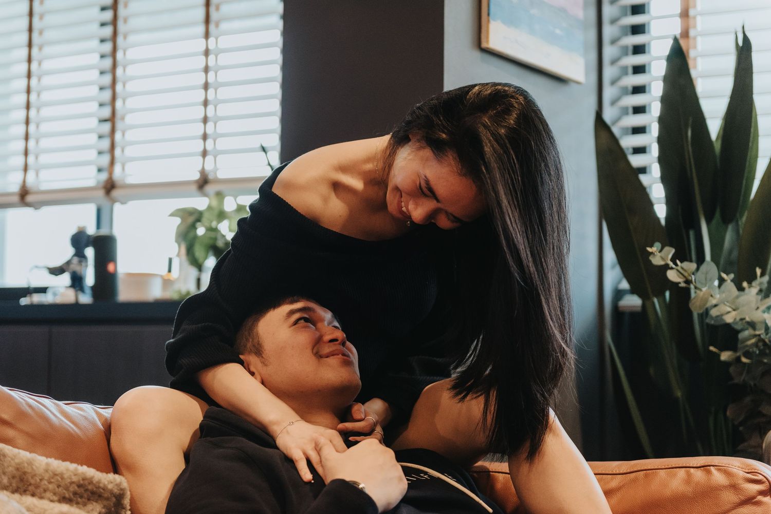 Intimate lifestyle portrait with natural window light and indoor plants as backdrop.