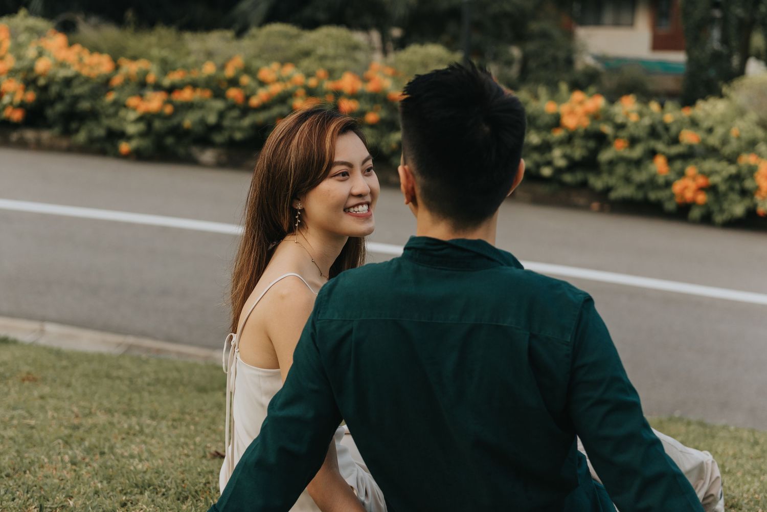 Casual outdoor photo session with couple near flowering bushes and pathway.