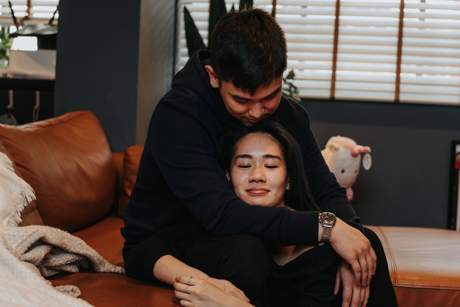 A sweet embrace captured on a leather couch with modern decor in the background.