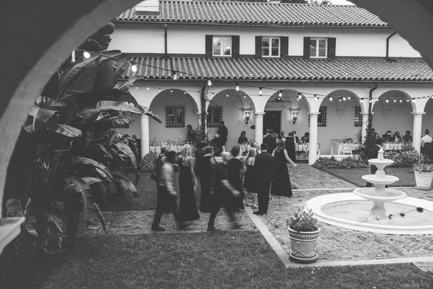 Documentary-style, film-inspired photograph of cocktail reception in Crane Cottage Courtyard at Jekyll Island Club wedding.
